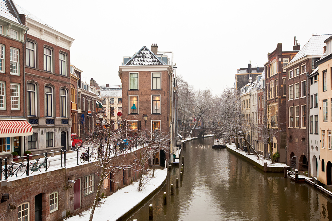 Wintertime Utrecht with snowy canals and historic bridges creating a charming, cozy scene.