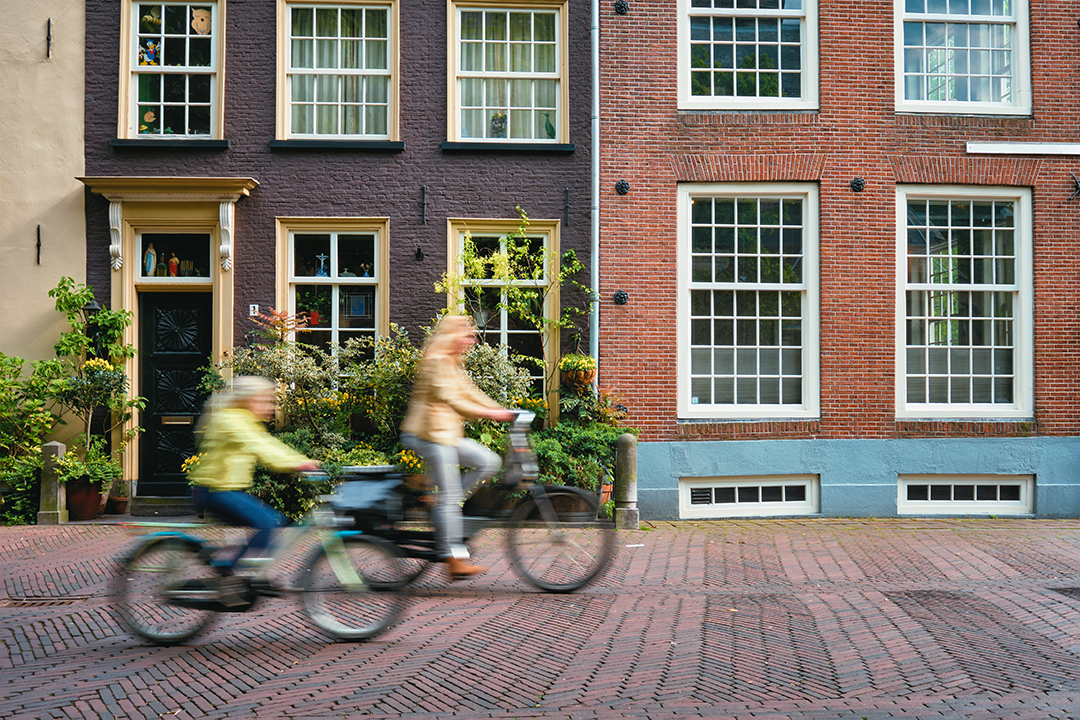 A cyclist gliding through Amsterdam’s quiet streets, capturing the essence of Dutch daily life.