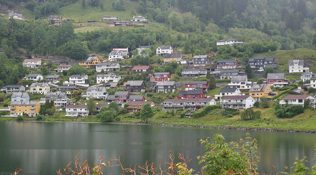 A peaceful lakeside view of hillside homes and surrounding greenery.