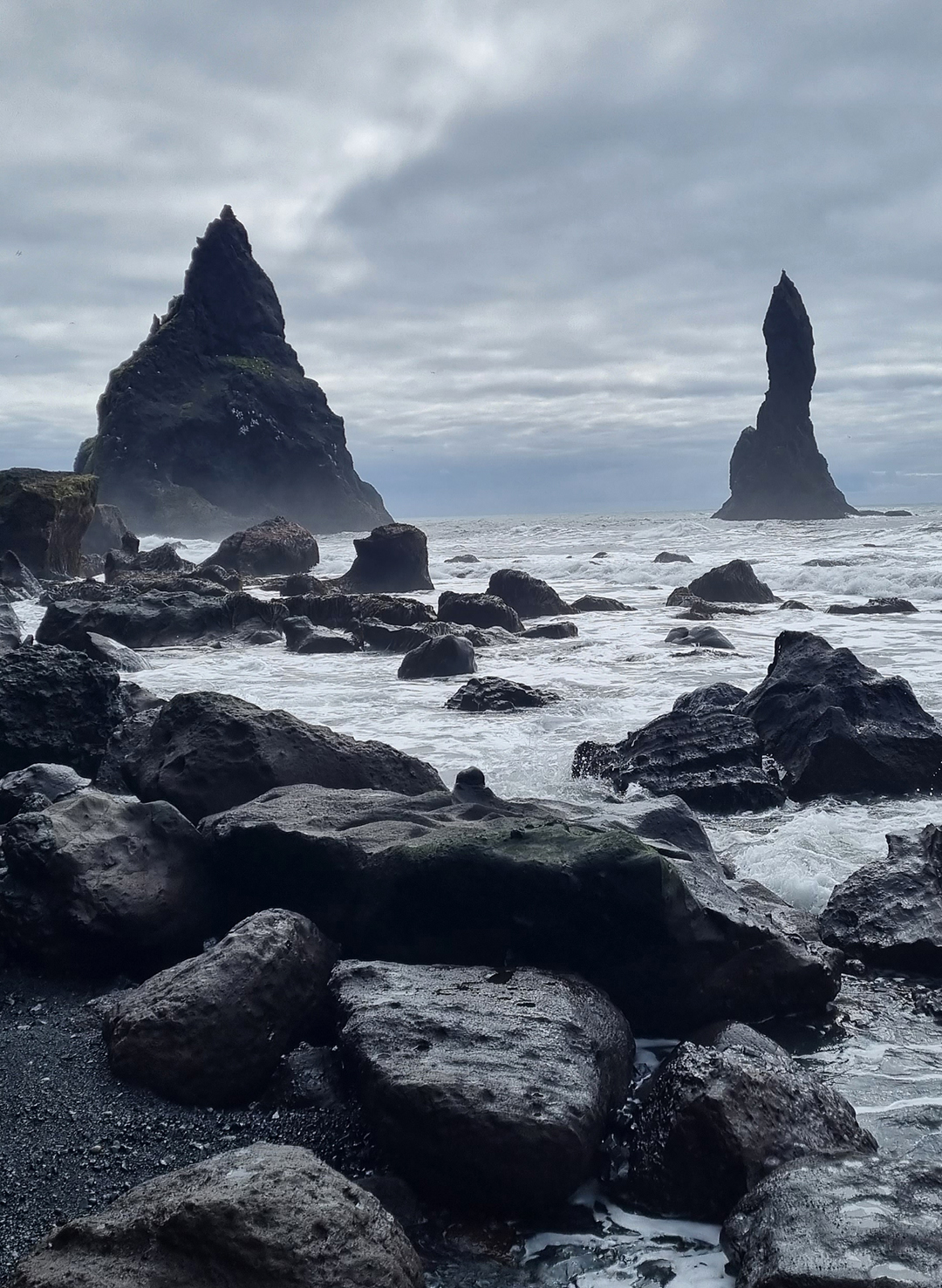 Reynisfjara black sand beach with dark volcanic sand, powerful Atlantic waves and dramatic coastal scenery in southern Iceland.