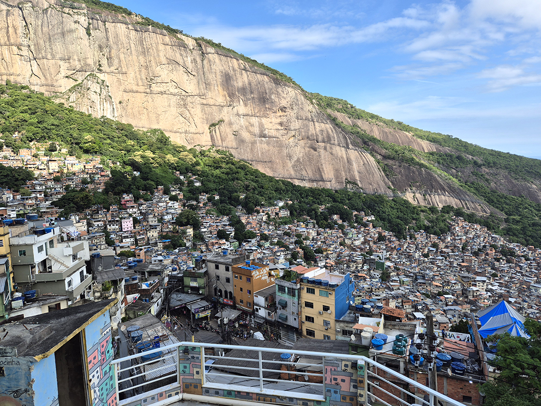 View of a densely populated favela in Rio de Janeiro beneath massive rock cliffs, highlighting the city’s contrasts and the importance of knowing safe areas when traveling in South America.