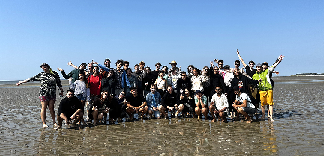 An international group of volunteers standing on the beach, symbolising collaboration, community and intercultural connection.