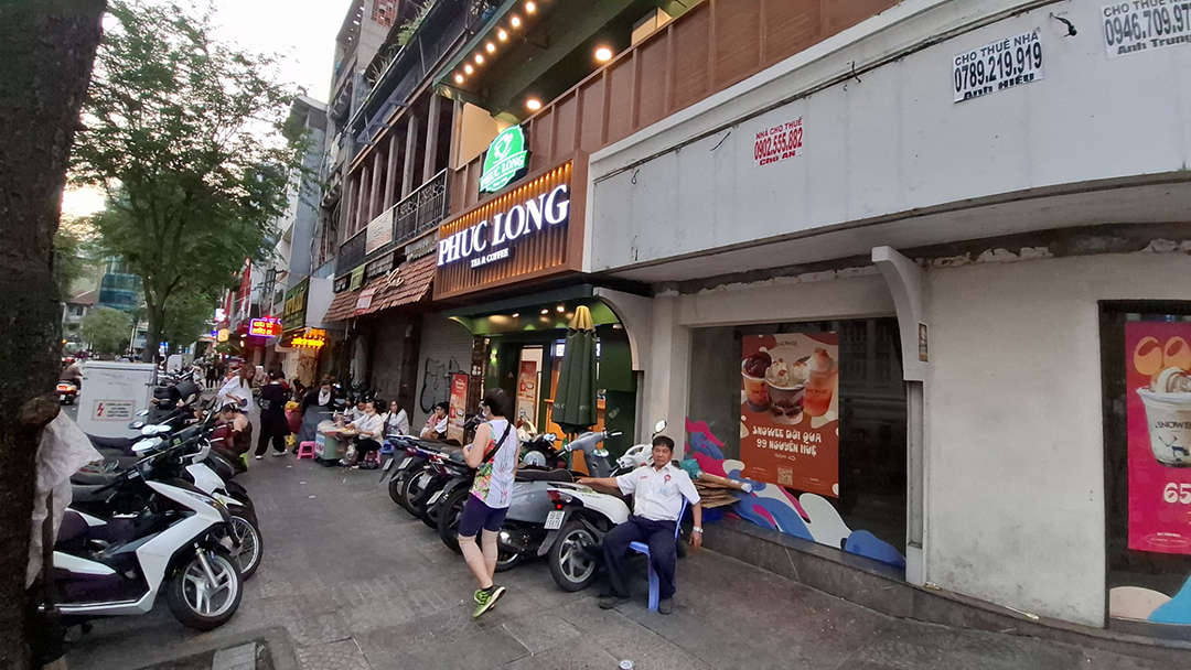 Typical Vietnamese street with a café, rows of motorbikes and locals relaxing in the warm afternoon bustle.