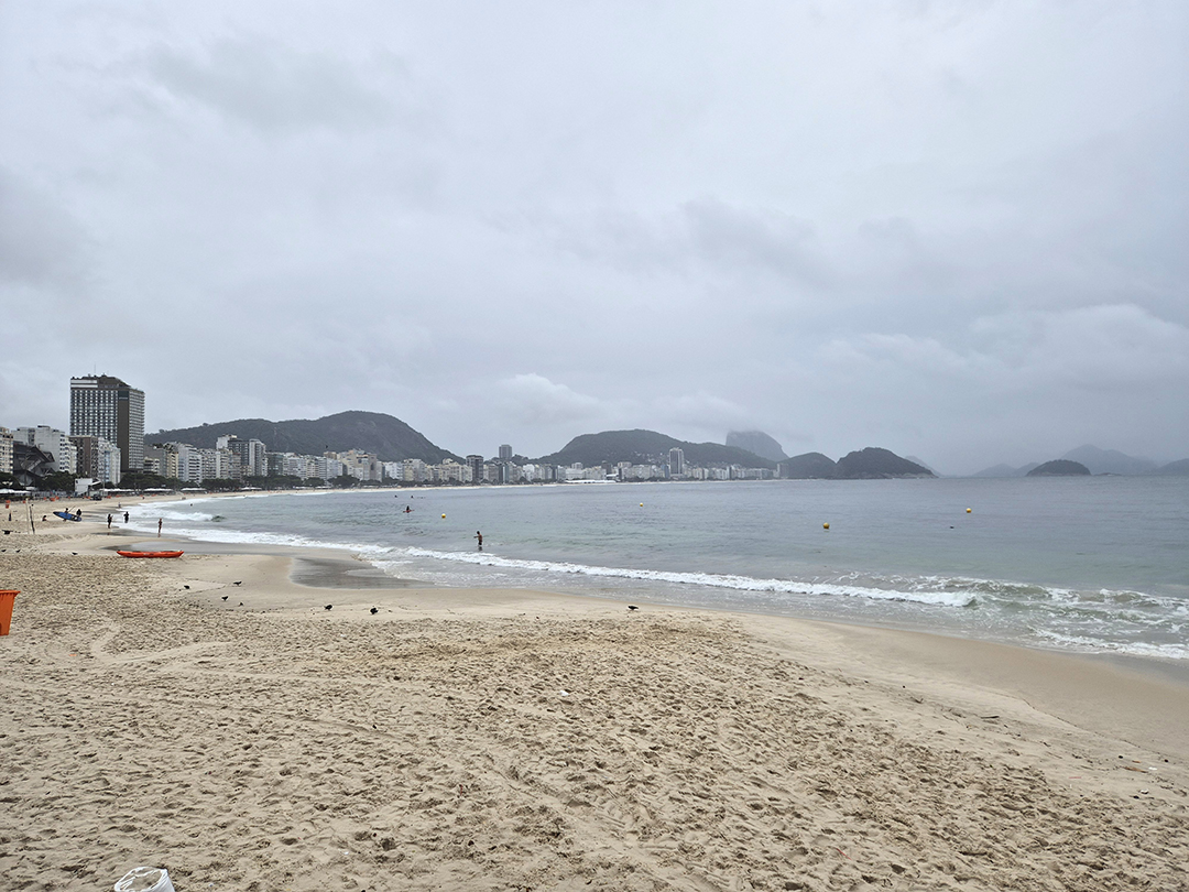 Cloudy view of the famous Copacabana beach in Rio de Janeiro, where the sandy coastline, Atlantic waves and city skyline meet the surrounding hills.