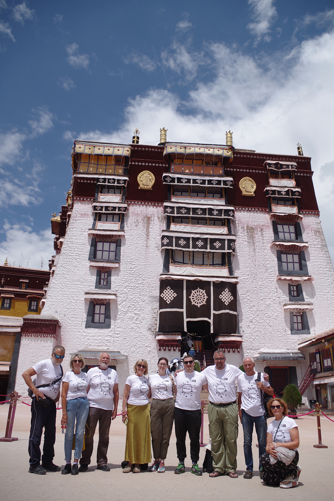 Skupina popotnikov pred tradicionalno tibetansko stavbo v kompleksu palače Potala v Lhasi.